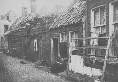 Foto uit 1914 aan de Moeskersgang in Groningen waaruit duidelijk de woningnood blijkt. Het dak van de woning is enigszins hersteld met asfaltpapier. Naast de woning een rommelhuisje, dat voorheen een openbare w.c. is geweest.